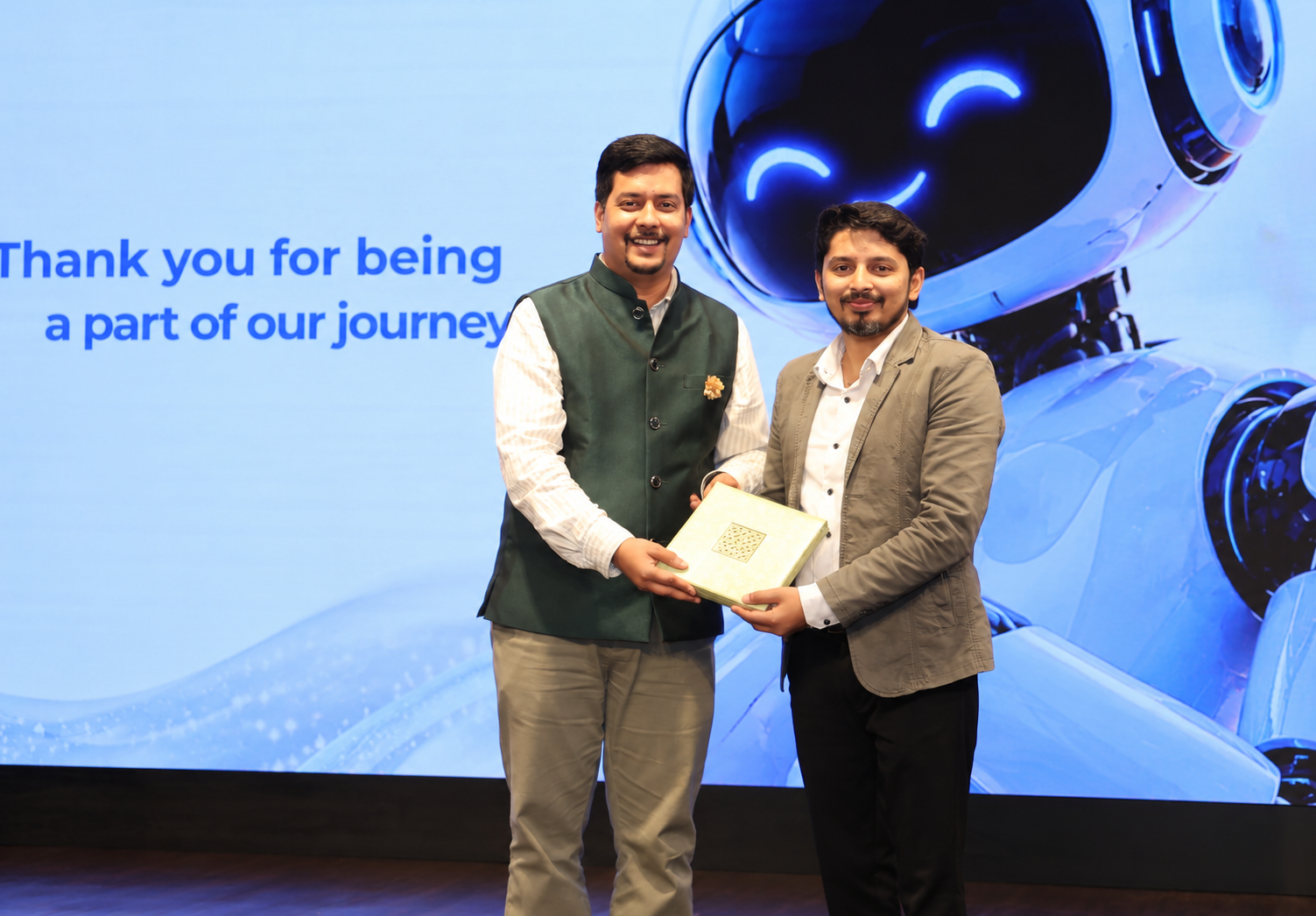 Vikram standing with another person holding a presentation gift